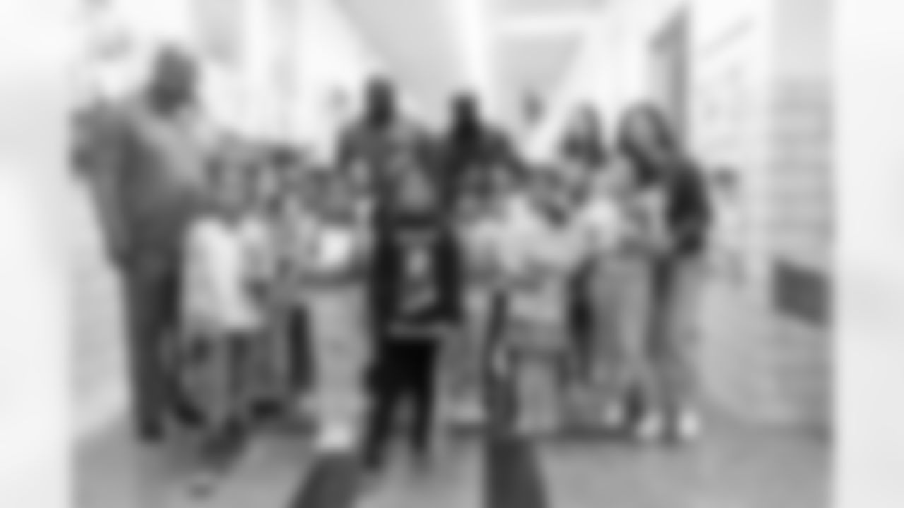 Kids pose with Denver Broncos alumni Kevin Clark, Reuben Droughns and Nick Ferguson during a book fair at Greenlee Elementary School in Denver, Colorado on April 10, 2024. Photo by Gabriel Christus / Denver Broncos