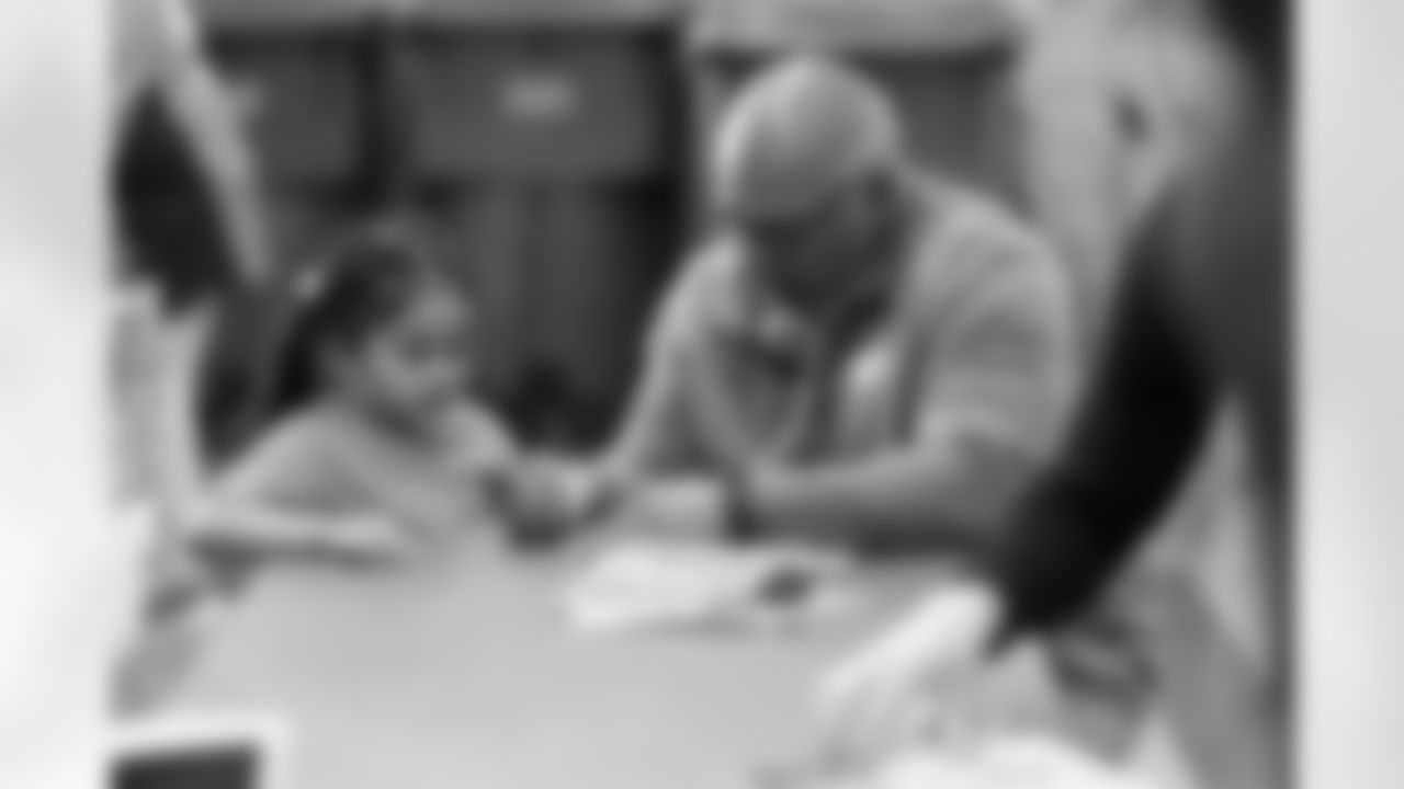 Kevin dClark helps a kid put her name in her books uring a book fair at Greenlee Elementary School in Denver, Colorado on April 10, 2024. Photo by Gabriel Christus / Denver Broncos