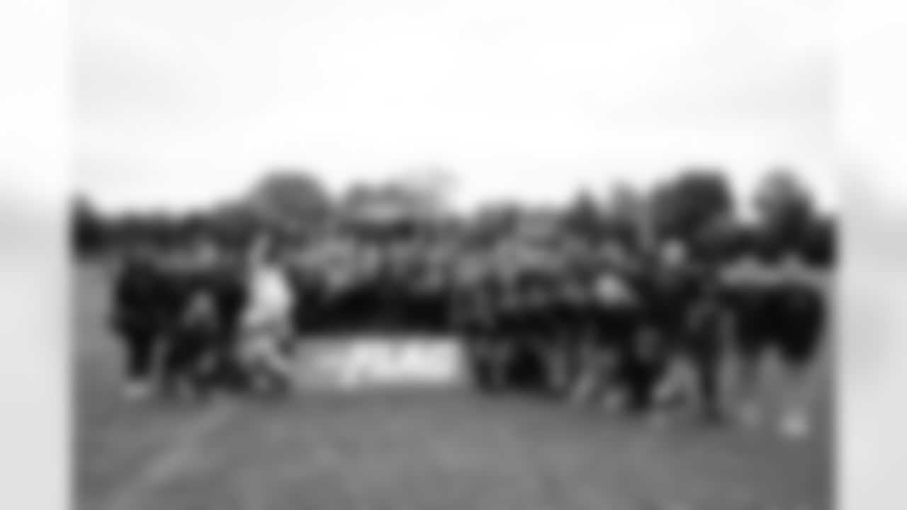 A group photo with students, DBC Mikayla, Carrie Walton Penner, DBC Brittany, Miles the Mascot, Steve Atwater, Bennie Fowler and Damani Leech at the Denver Broncos flag football clinic at Grey Court School in Richmond, England on October 9, 2025. Photo by Ben Swanson / Denver Broncos