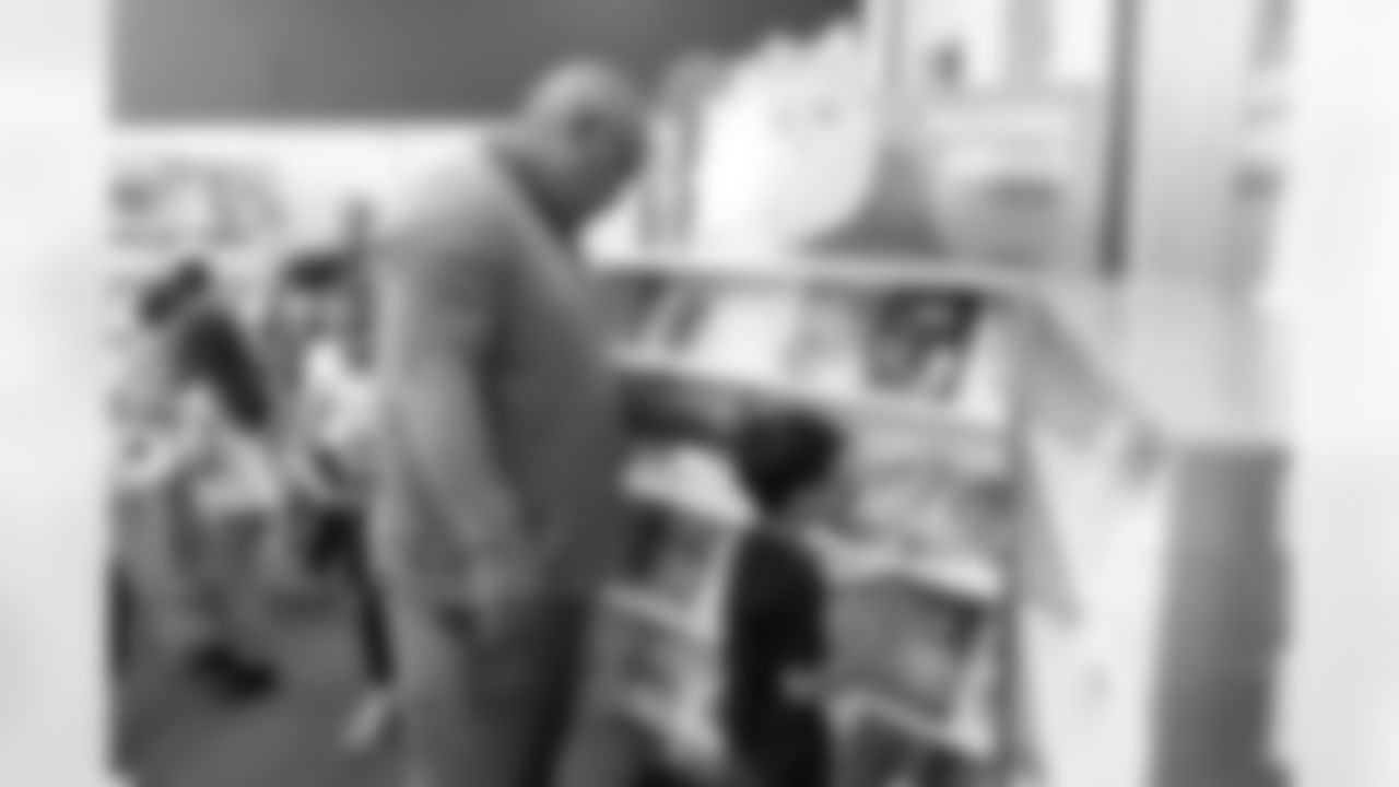Kevin Clark helps a kid pick out his book during a book fair at Greenlee Elementary School in Denver, Colorado on April 10, 2024. Photo by Gabriel Christus / Denver Broncos