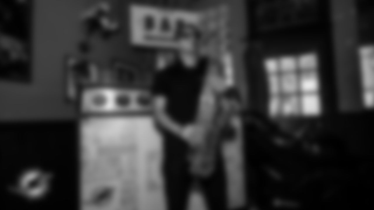 A man plays the saxophone in front of the DJ booth at The Bar.