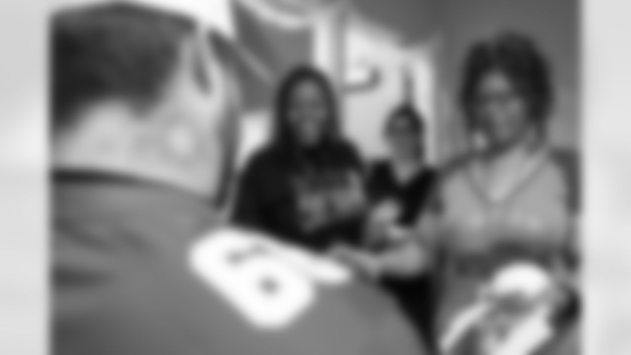 Alternatives for Girls employees receiving an autograph from Detroit Lions tackle Taylor Decker (68) during a Thanksgiving lunch event at Alternatives For Girls on Nov. 28, 2025 in Detroit. (Izzy Rincon/Detroit Lions)