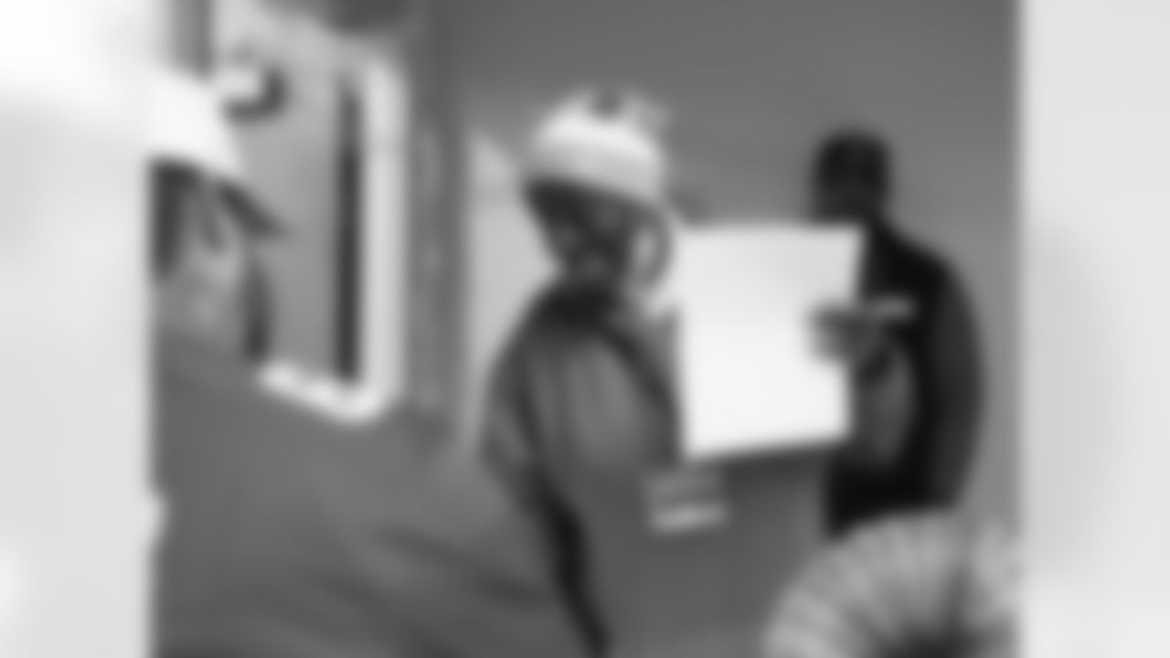 An Alternatives for Girls employee receiving an autograph from Detroit Lions tackle Taylor Decker (68) during a Thanksgiving lunch event at Alternatives For Girls on Nov. 28, 2025 in Detroit. (Izzy Rincon/Detroit Lions)