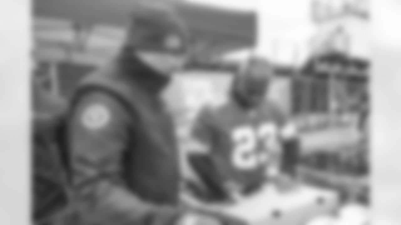 Lions Legend Maurice Harvey (23) helps a volunteer unpack turkeys during a Thanksgiving meal kit distribution event at the Detroit Lions Academy in Detroit, MI on November 20, 2024. (Mike Ferdinande/Detroit Lions)