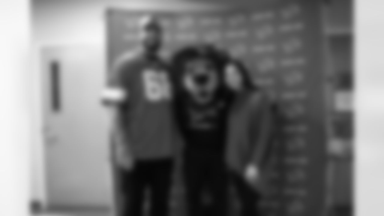 Detroit Lions tackle Taylor Decker (68), Detroit Lions Mascot Roary and Kyndra Decker pose for a photo during a Thanksgiving lunch event at Alternatives For Girls on Nov. 28, 2025 in Detroit. (Izzy Rincon/Detroit Lions)