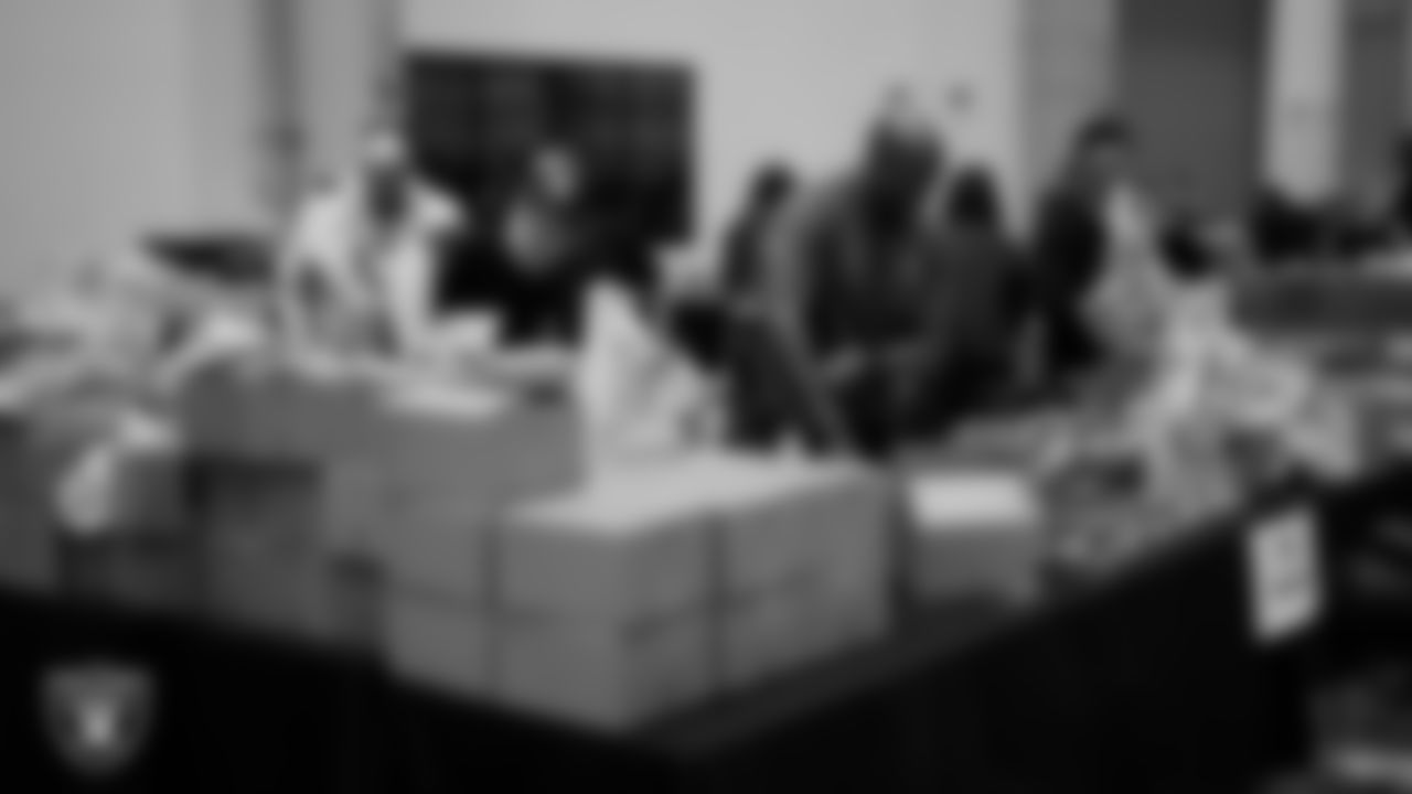 Las Vegas Raiders staff members help pack meals during the Raiders Holiday Meal Packing Party at Intermountain Health Performance Center.