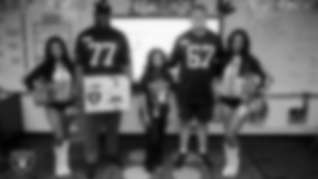 Raiderettes Kylee and Cierra and Las Vegas Raiders tackle Thayer Munford Jr. (77) and center Will Putnam (67) pose for a photo with a teacher while celebrating Teacher Appreciation Week at Matt Kelly Elementary School.