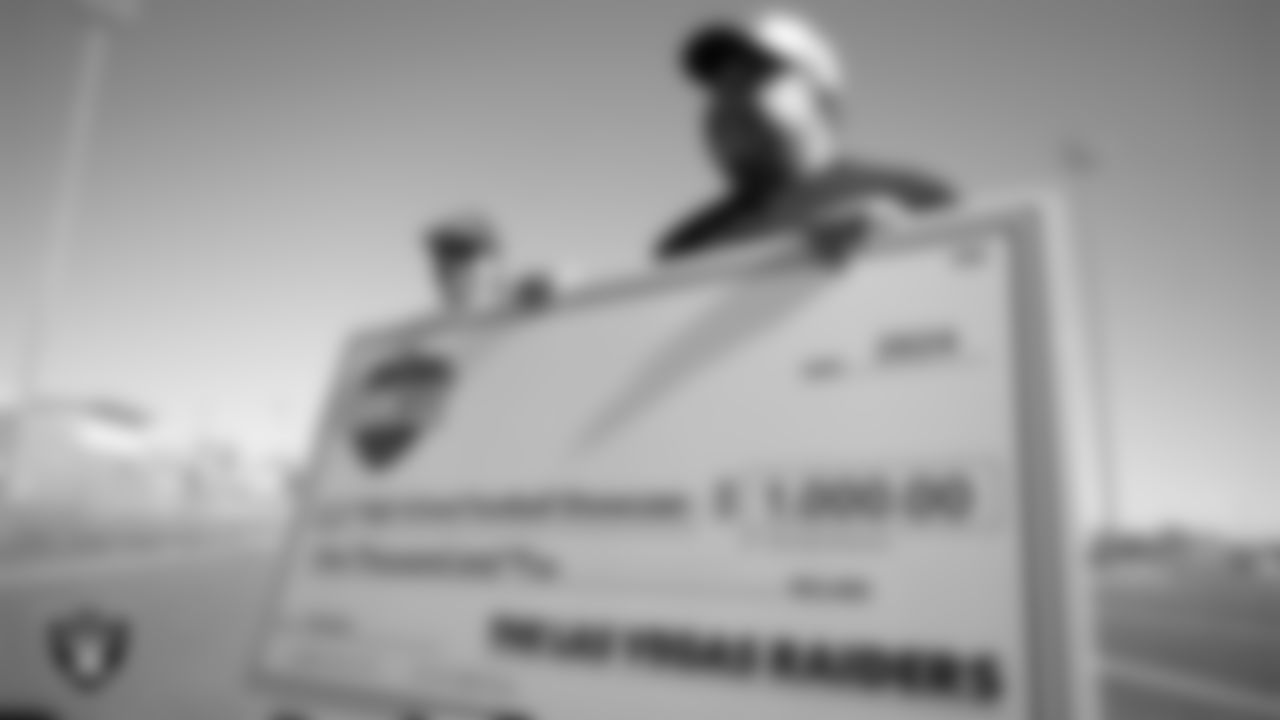 Las Vegas Raiders senior manager of football development Jordan Aguilar presents the Boulder City High School football team with a check during practice Boulder City High School.