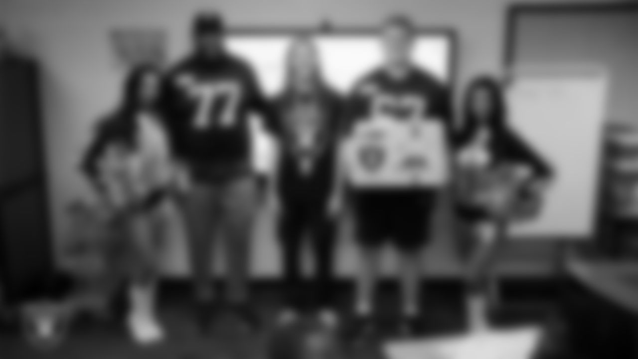 Raiderettes Cierra and Kylee and Las Vegas Raiders tackle Thayer Munford Jr. (77) and center Will Putnam (67) pose for a photo with a teacher while celebrating Teacher Appreciation Week at Matt Kelly Elementary School.