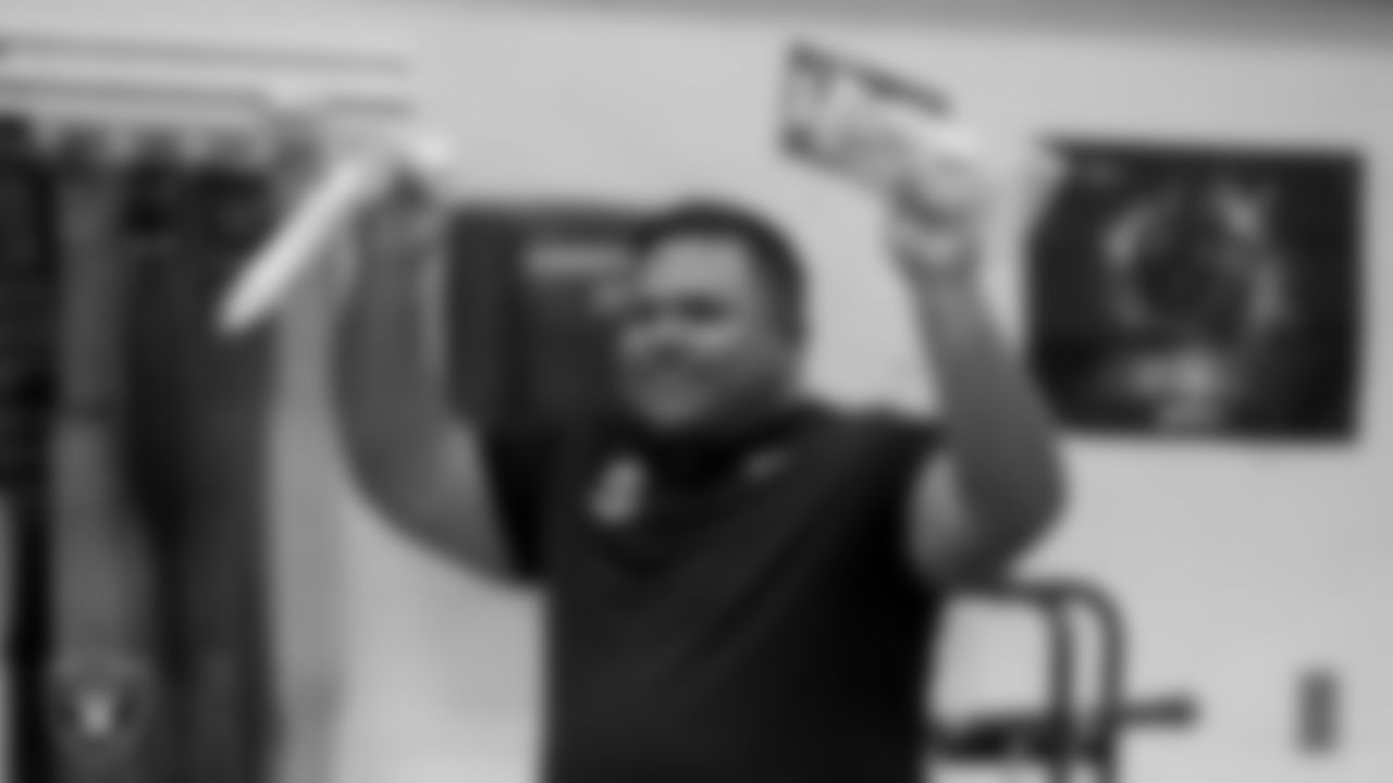 Las Vegas Raiders senior manager of football development Jordan Aguilar hands out gloves to the Legacy High School football team during practice at Legacy High School.