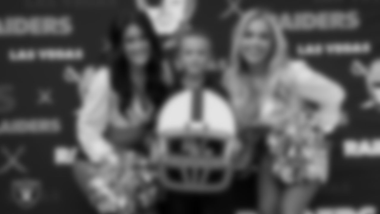 Raiderettes Macy and Devyn pose for a photo with an athlete during Silver and Black Saturday at McCarran Marketplace Park.