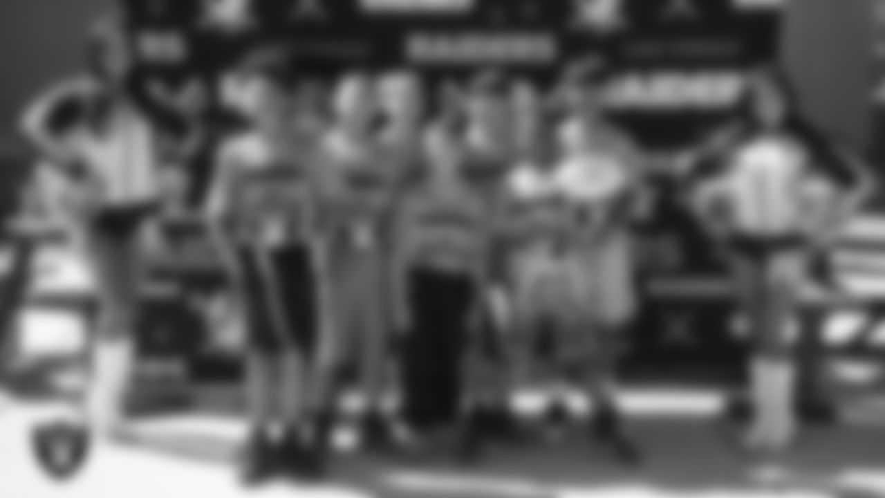 Raiderettes Cheyanne and Tatiana pose for a photo with athletes before a Silver and Black Flag Football game at Bill and Lillie Heinrich YMCA.