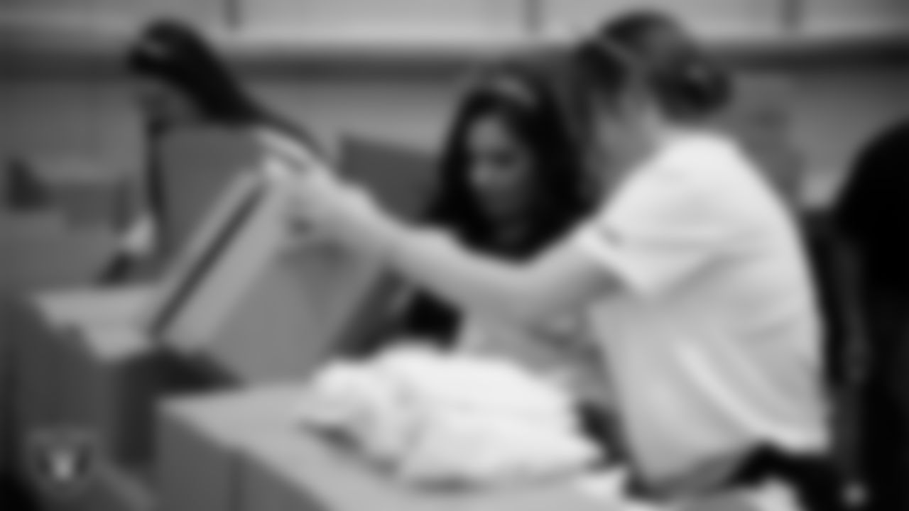 Las Vegas Raiders staff members help pack meals during the Raiders Holiday Meal Packing Party at Intermountain Health Performance Center.