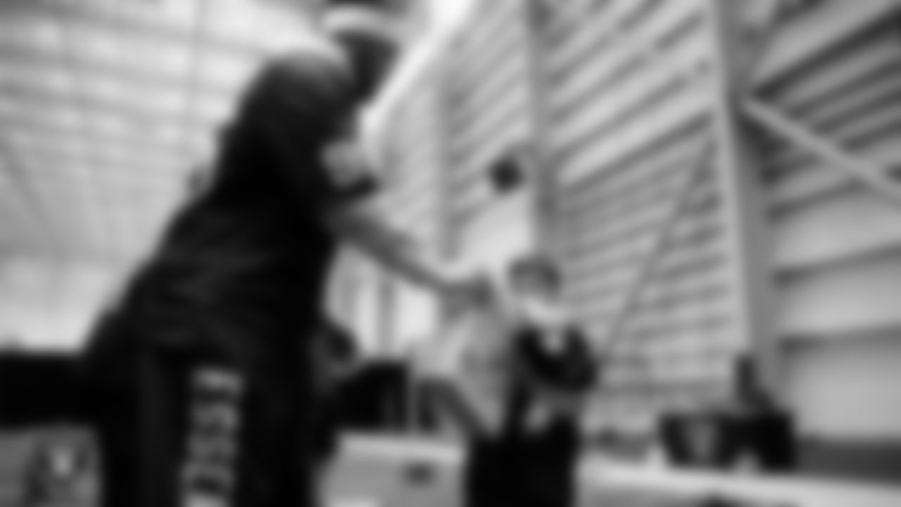 Las Vegas Raiders defensive tackle Jonah Laulu (96) helps a student select toys during a Raiders Youth Holiday Party at Intermountain Health Performance Center.