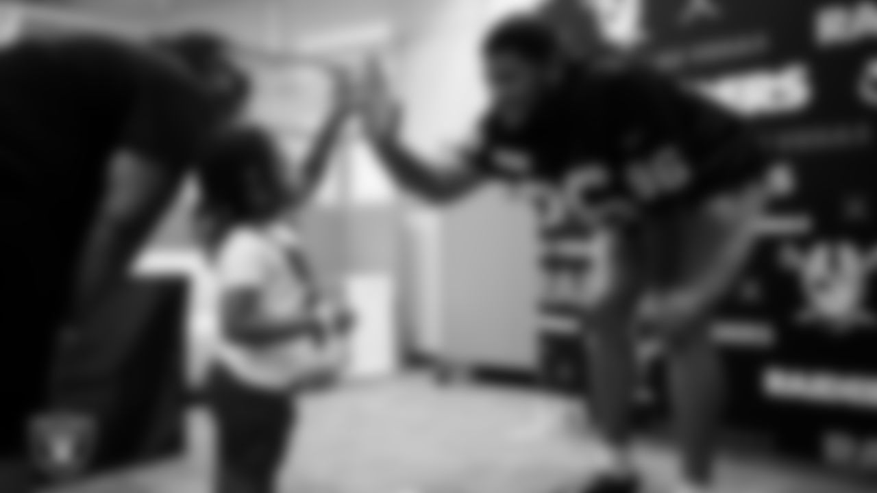 Las Vegas Raiders defensive tackle Jonah Laulu (96) high-fives a guest during a launch event at Aliante Library.