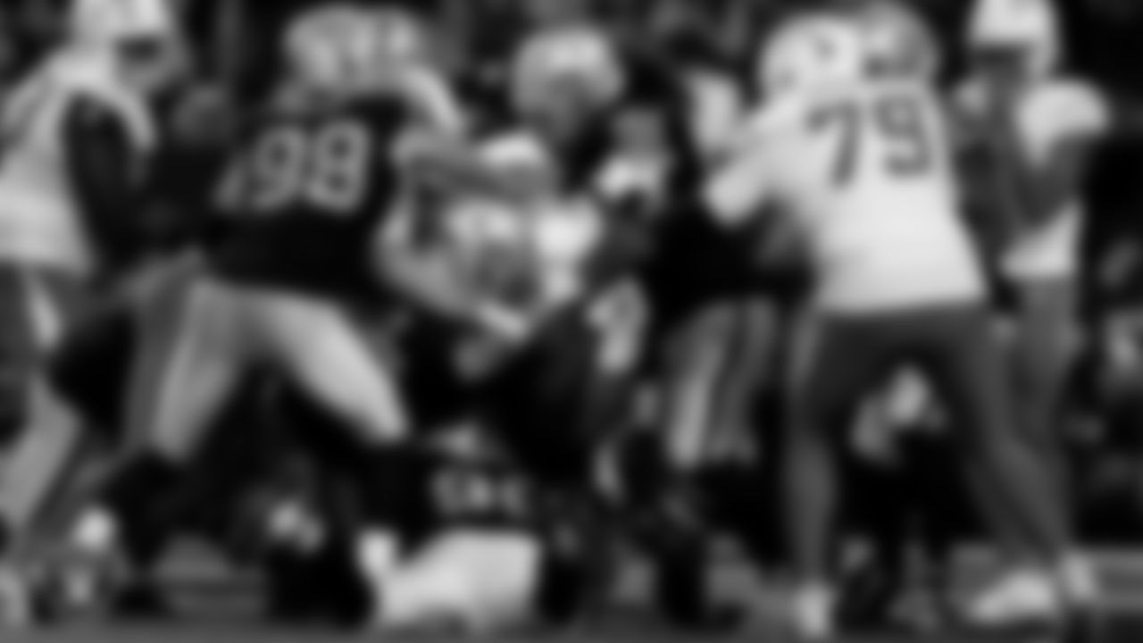 Las Vegas Raiders defensive end Maxx Crosby (98), defensive tackle Adam Butler (69), defensive tackle Jonah Laulu (96) and defensive tackle Leki Fotu (95) make a tackle during the regular season home game against the Los Angeles Chargers at Allegiant Stadium.