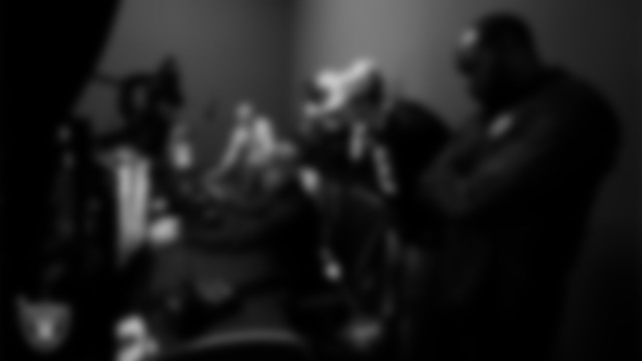 A service member speaks with Las Vegas Raiders players and alumni about a simulator during a tour of Nellis Air Force Base.