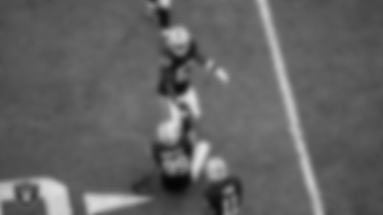 Las Vegas Raiders linebacker Germaine Pratt (57) helps defensive tackle Thomas Booker IV (99) on the field during the regular season home game against the Chicago Bears at Allegiant Stadium.