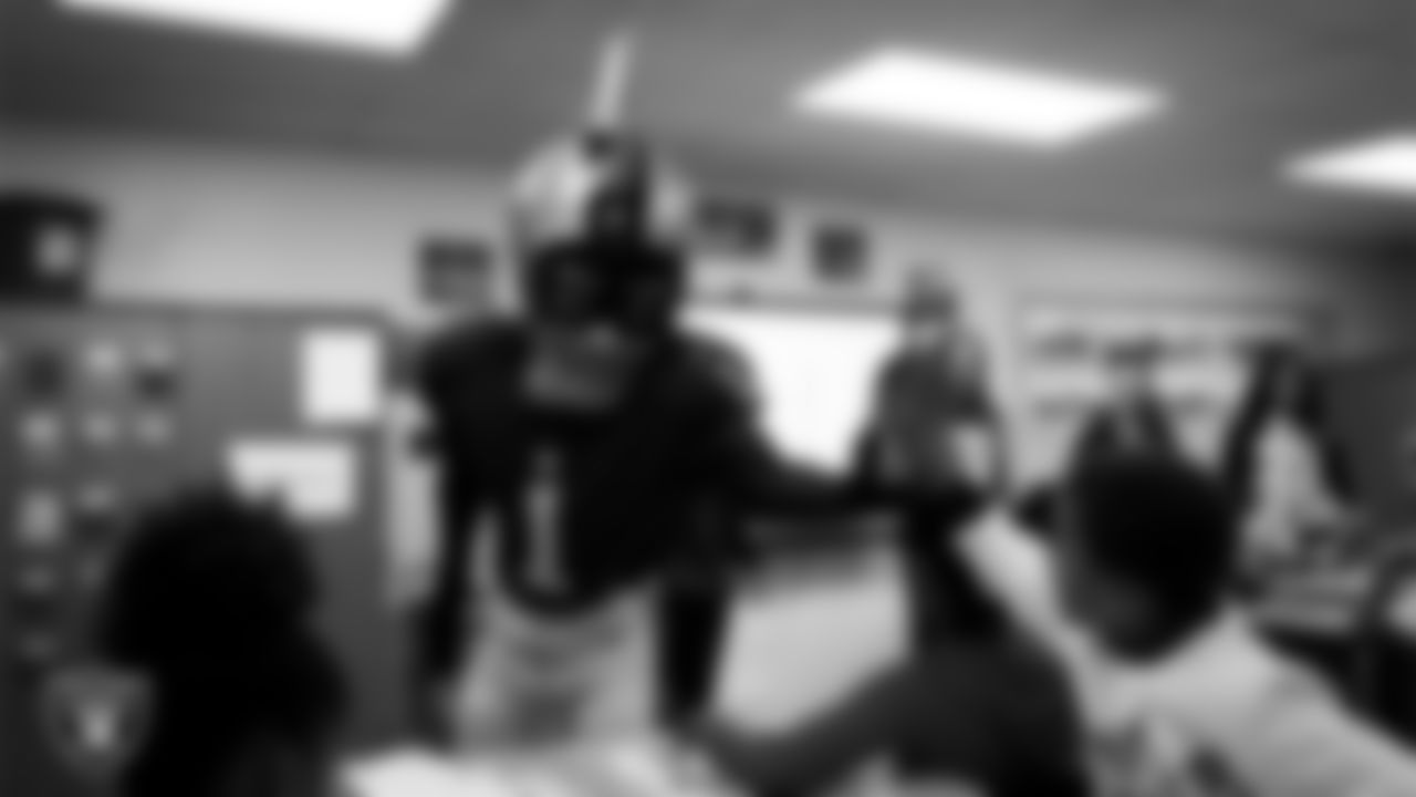 Raider Rusher gives a high-five to a student during a 'Lil Raiders Pop-Up at Matt Kelly Elementary School.