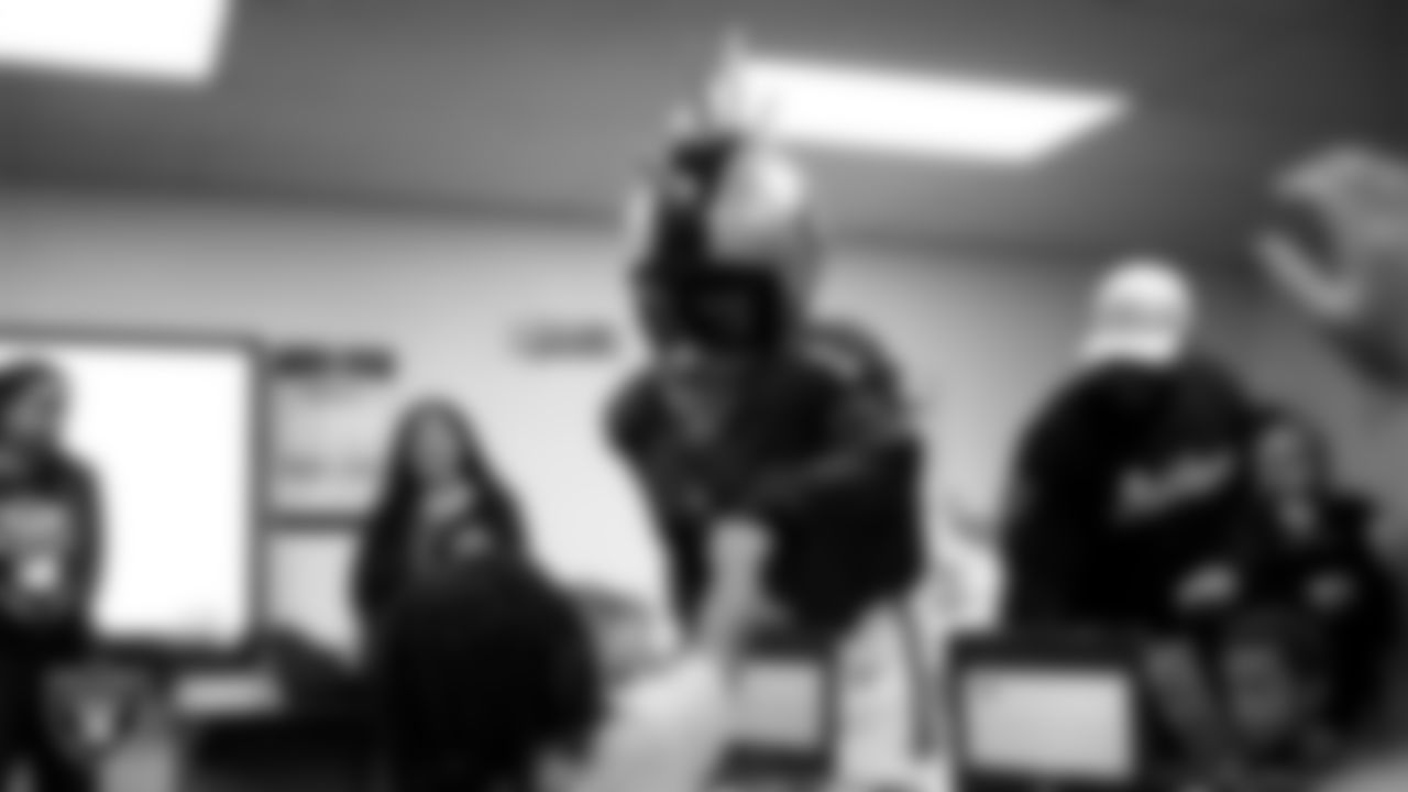 Raider Rusher gives a fist bump to a student during a 'Lil Raiders Pop-Up at Matt Kelly Elementary School.