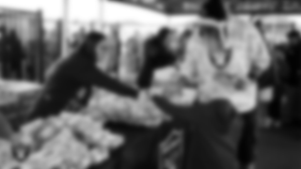 Volunteers hand out apples from Melissa's Produce during the Raiders Holiday Salute at Nellis Air Force Base - Coral Academy.