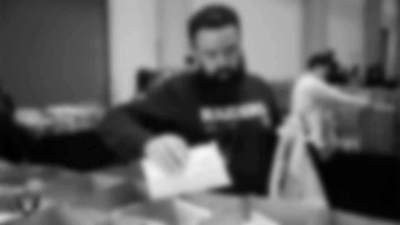 Las Vegas Raiders staff members help pack meals during the Raiders Holiday Meal Packing Party at Intermountain Health Performance Center.