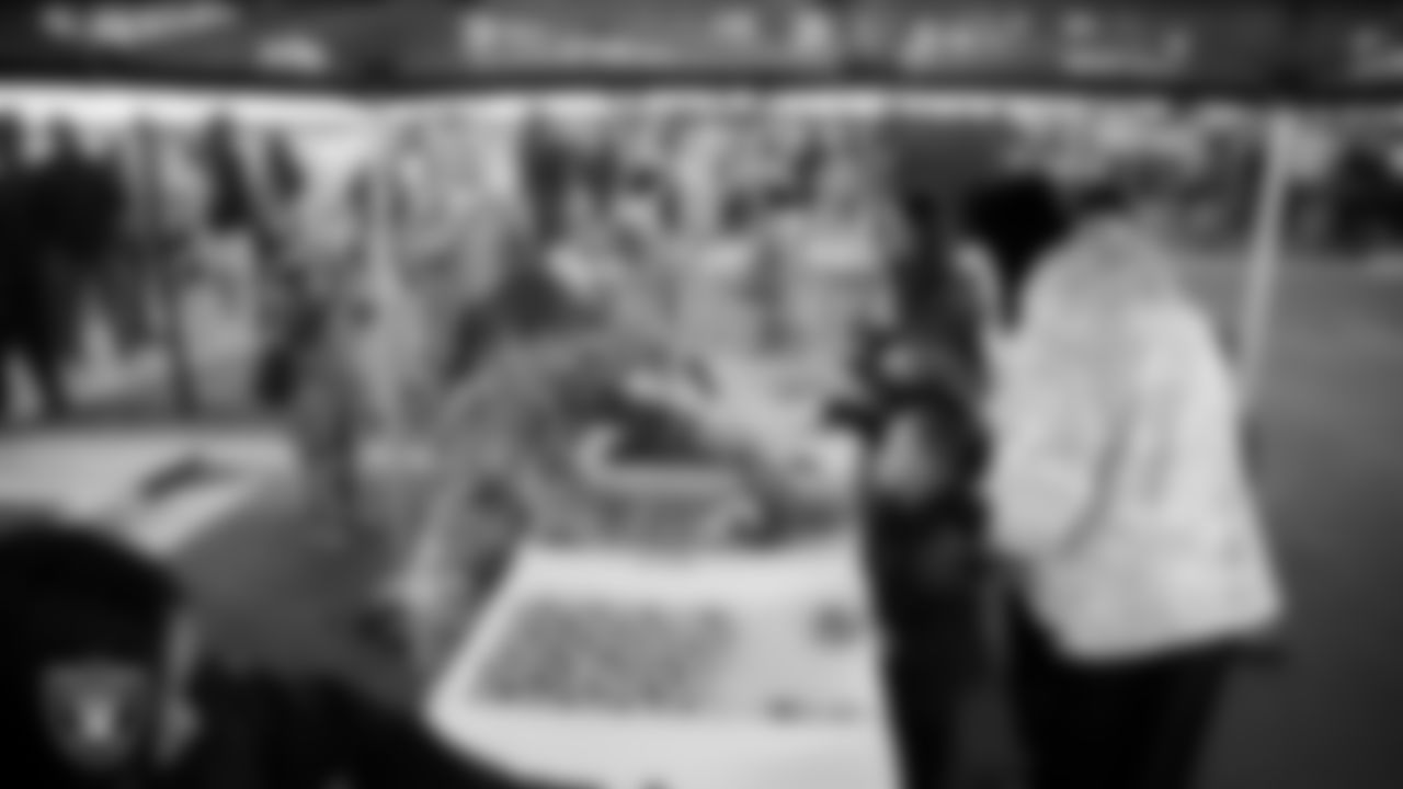 Air Force members hand out Pinkbox doughnuts during the Raiders Holiday Salute at Nellis Air Force Base - Coral Academy.