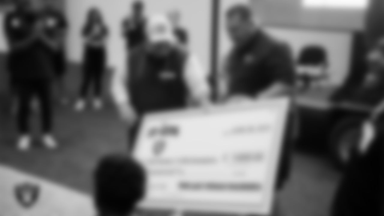 Las Vegas Raiders senior manager of football development Jordan Aguilar presents a check to the winning team during the 11-ON at Intermountain Health Performance Center