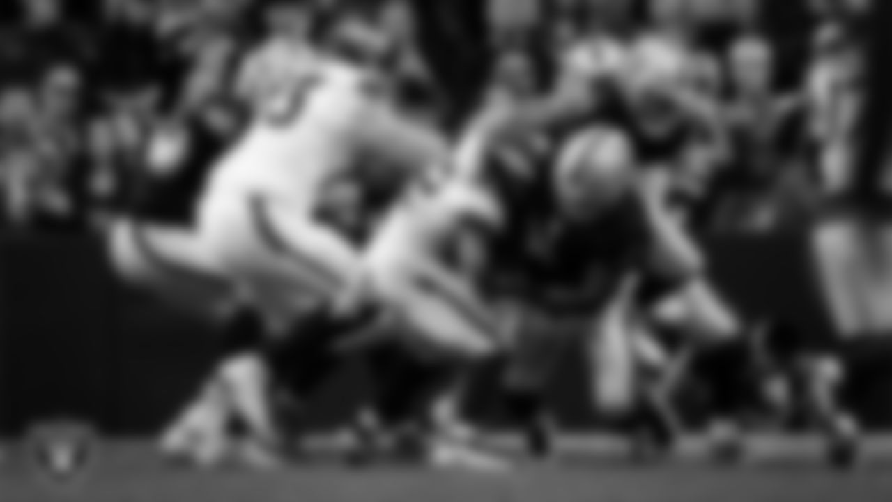 Las Vegas Raiders defensive end Maxx Crosby (98) and safety Jeremy Chinn (11) make a tackle during the regular season home game against the Denver Broncos at Allegiant Stadium.