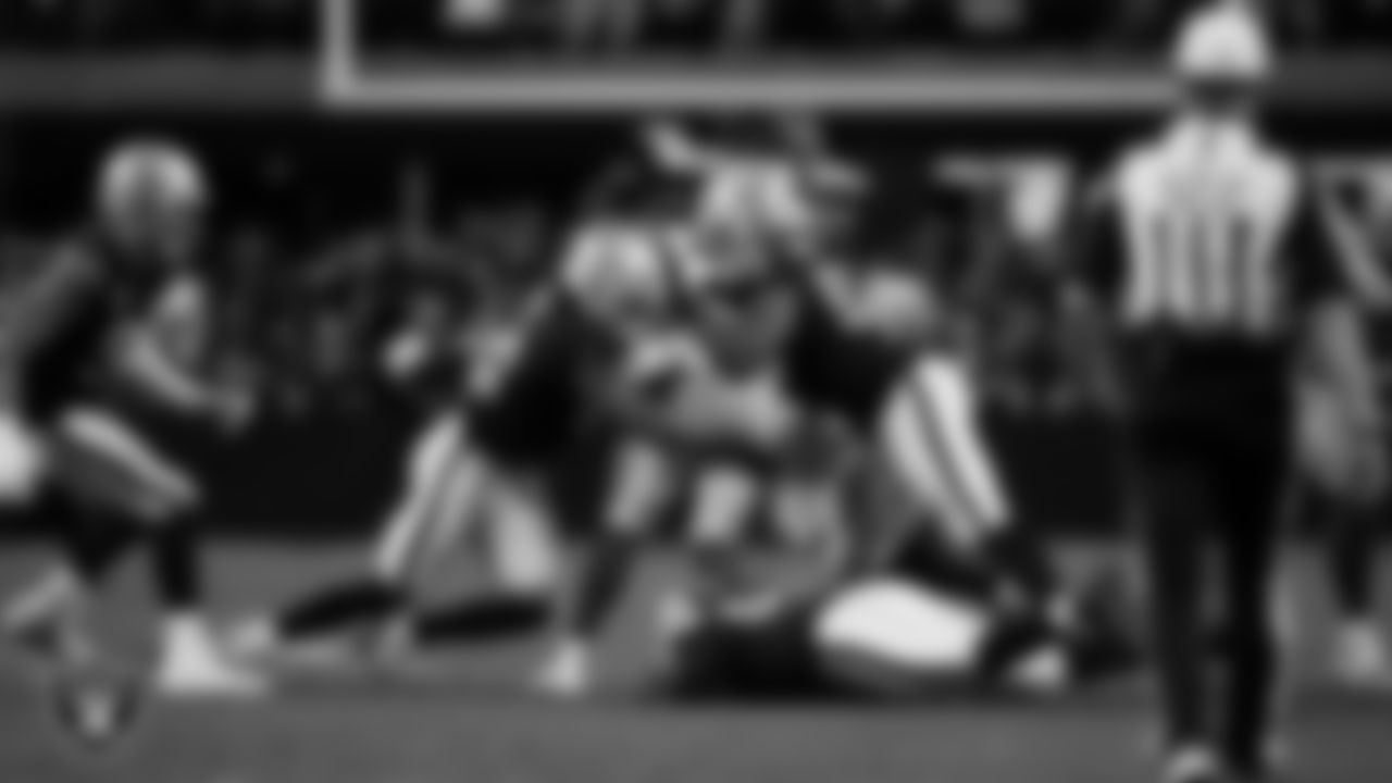 Las Vegas Raiders safety Jeremy Chinn (11) and defensive tackle Thomas Booker IV (99) make a tackle during the regular season home game against the Dallas Cowboys at Allegiant Stadium.