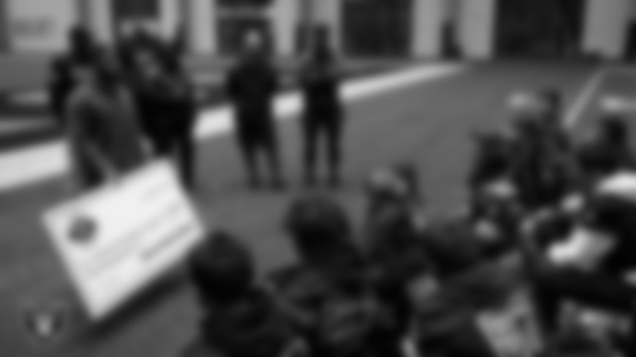 Las Vegas Raiders coordinator of football development Chris Shelby present athletes with a check to go towards their travels for nationals during an open practice at Intermountain Health Performance Center.