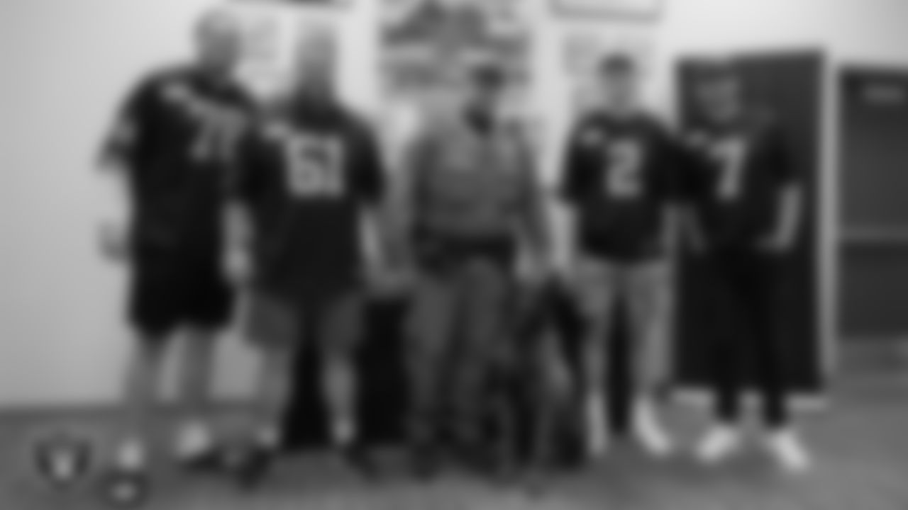 Las Vegas Raiders tackle Dalton Wagner (78), offensive lineman Jordan Meredith (61), kicker Daniel Carlson (2) and quarterback Brian Hoyer (7) pose for a photo with K-9 Raider and his handler Officer Corbett during a visit to William Fortye K-9 Operations Center.