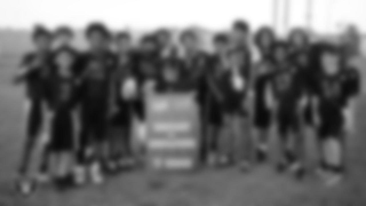 Raider Rusher poses for a photo with the Charles Silvestri Junior High School boys flag football team after the Las Vegas Raiders' Middle School Flag Football Showcase game at Charles Silvestri Junior High School.