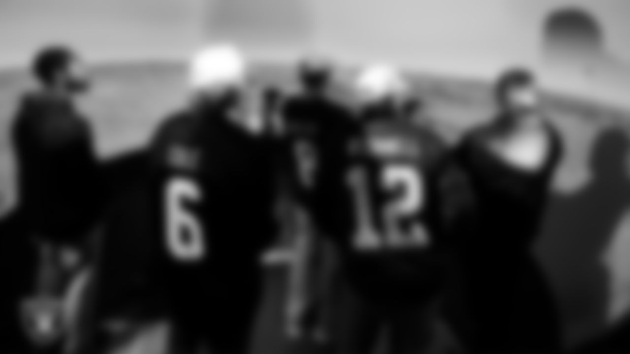 A service member speaks with Las Vegas Raiders players and alumni about a simulator during a tour of Nellis Air Force Base.