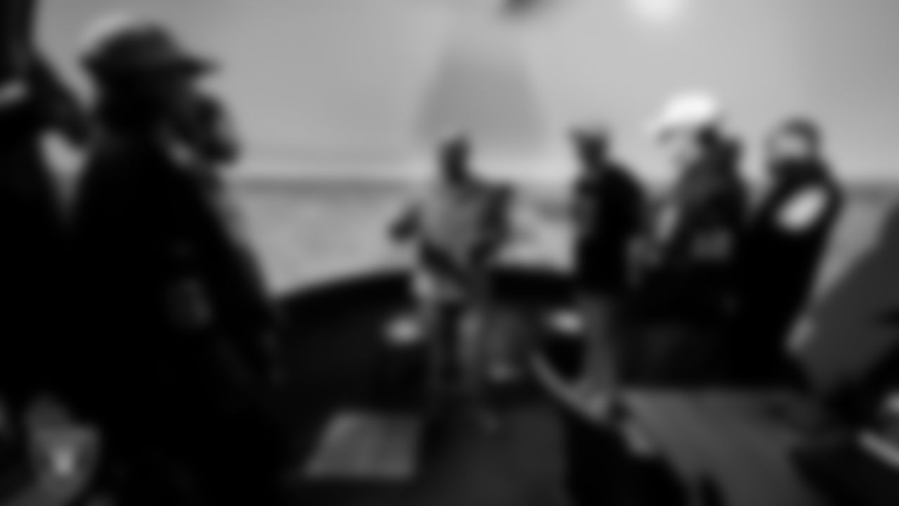 A service member speaks with Las Vegas Raiders players and alumni about a simulator during a tour of Nellis Air Force Base.