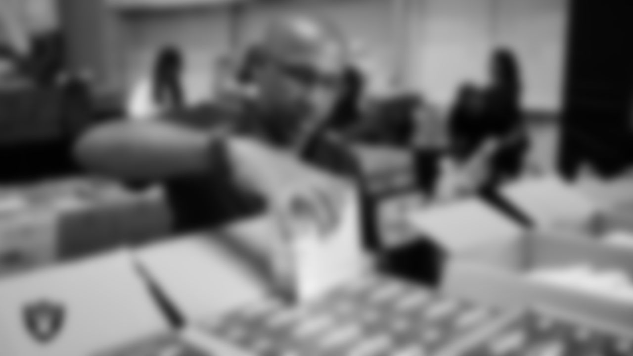 Las Vegas Raiders staff members help pack meals during the Raiders Holiday Meal Packing Party at Intermountain Health Performance Center.