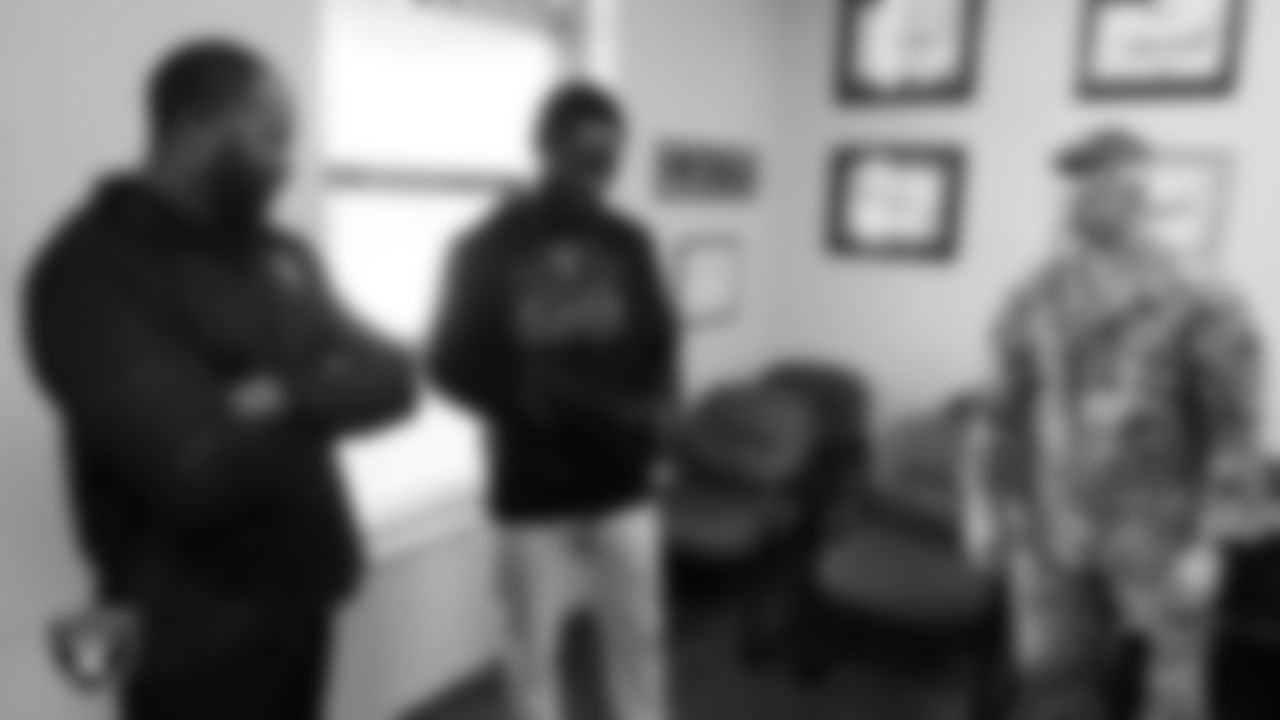 Las Vegas Raiders alumni Darren McFadden and Cory Littleton look over military equipment with a service member during a tour of Nellis Air Force Base.