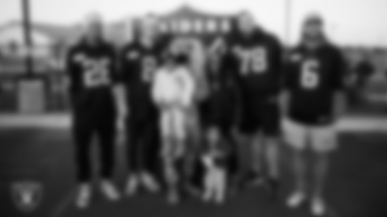 Las Vegas Raiders cornerback Darien Porter (26), kicker Daniel Carlson (8), tackle Dalton Wagner (78) and punter AJ Cole (6) pose for a photo with an Air Force family during the Raiders Holiday Salute at Nellis Air Force Base - Coral Academy.