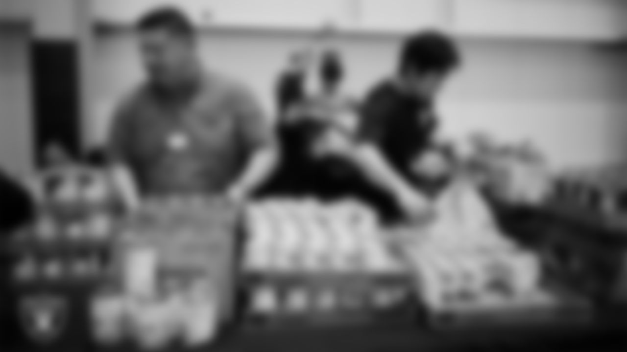 Las Vegas Raiders staff members help pack meals during the Raiders Holiday Meal Packing Party at Intermountain Health Performance Center.