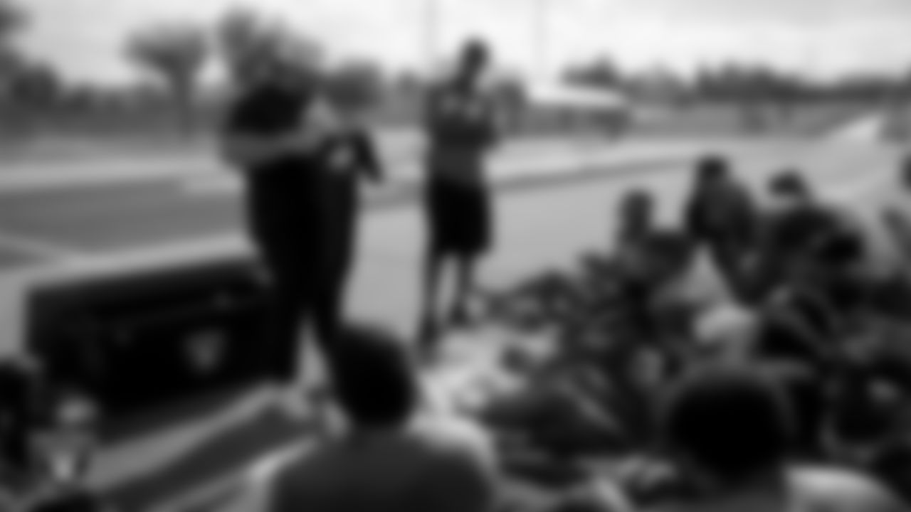 Las Vegas Raiders senior manager of football development Jordan Aguilar hands out High School Showcase t-shirts to the Canyon Springs High School football team during practice at Canyon Springs High School.