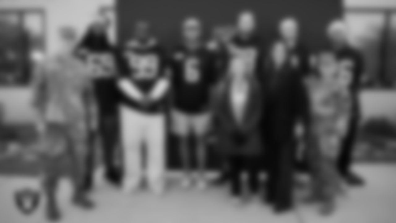 Las Vegas Raiders defensive tackle Adam Butler (69), defensive tackle Thomas Booker IV (99), punter AJ Cole (6), tackle Dalton Wagner (78), kicker Daniel Carlson (8) and cornerback Dairen Porter (26) pose for a photo with Air Force members and Coral Academy staff members during the Raiders Holiday Salute at Nellis Air Force Base - Coral Academy.