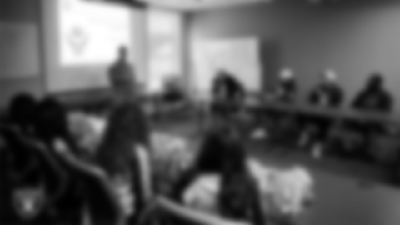 A service member speaks with Las Vegas Raiders players, alumni and Raiderettes about training that takes place on base during a tour of Nellis Air Force Base.