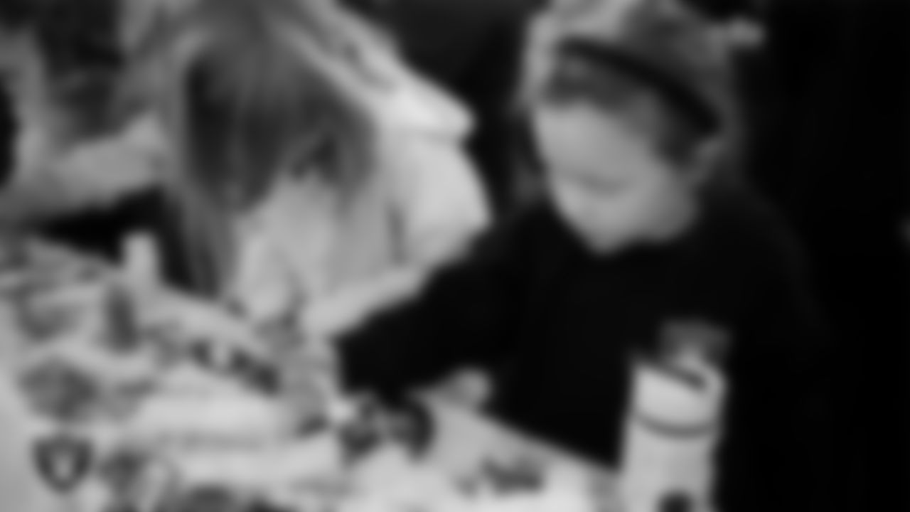 Children decorate cookies during the Raiders Holiday Salute at Nellis Air Force Base - Coral Academy.