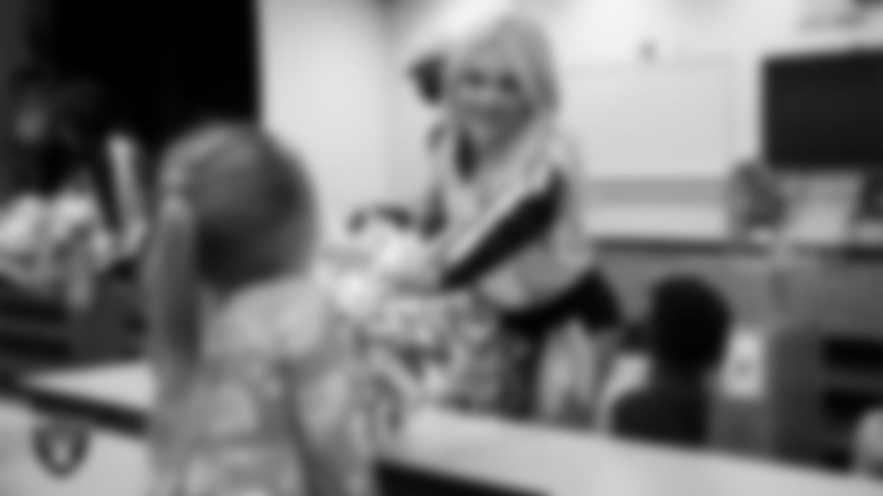 Raiderette Pip speaks to a student during a 'Lil Raiders Pop-Up at Matt Kelly Elementary School.