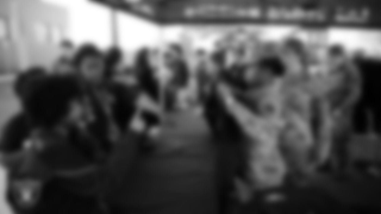 Air Force members hand out Raiders gear during the Raiders Holiday Salute at Nellis Air Force Base - Coral Academy.