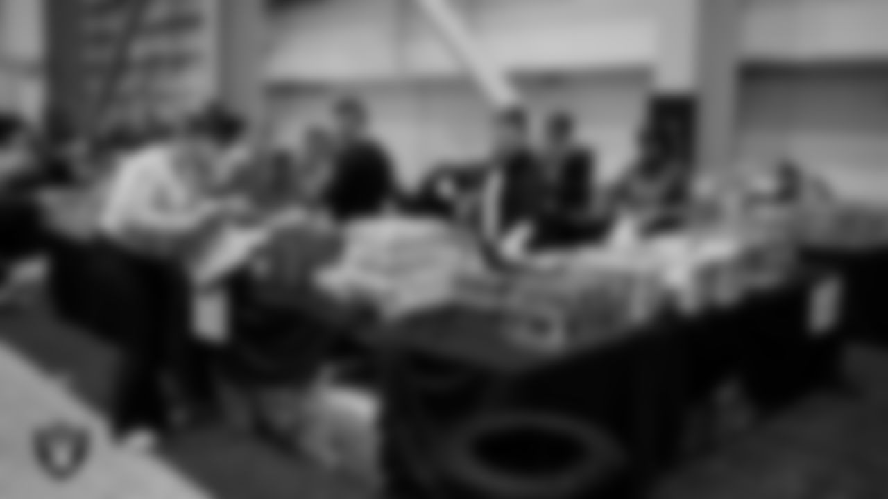 Las Vegas Raiders staff members help pack meals during the Raiders Holiday Meal Packing Party at Intermountain Health Performance Center.