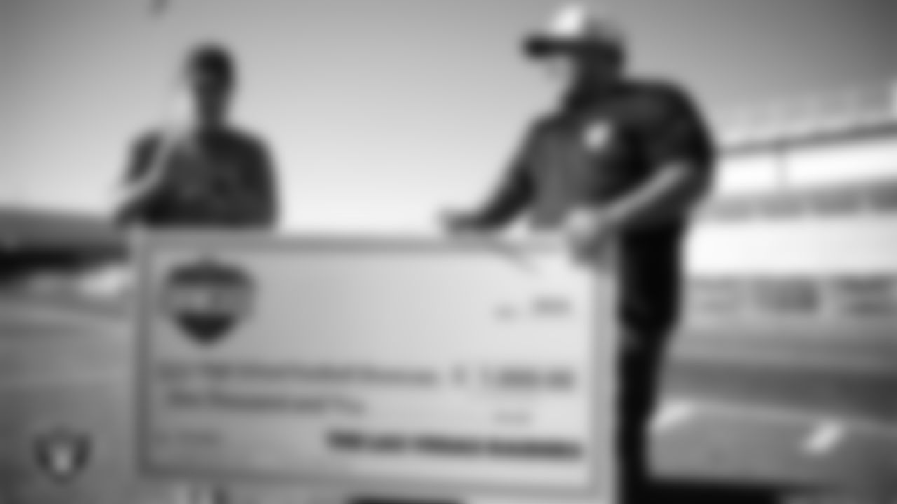 Las Vegas Raiders senior manager of football development Jordan Aguilar presents a check to Somerset Academy Losee football coach Dan Branson during practice at Somerset Academy Losee.