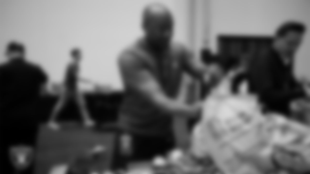 Las Vegas Raiders staff members help pack meals during the Raiders Holiday Meal Packing Party at Intermountain Health Performance Center.