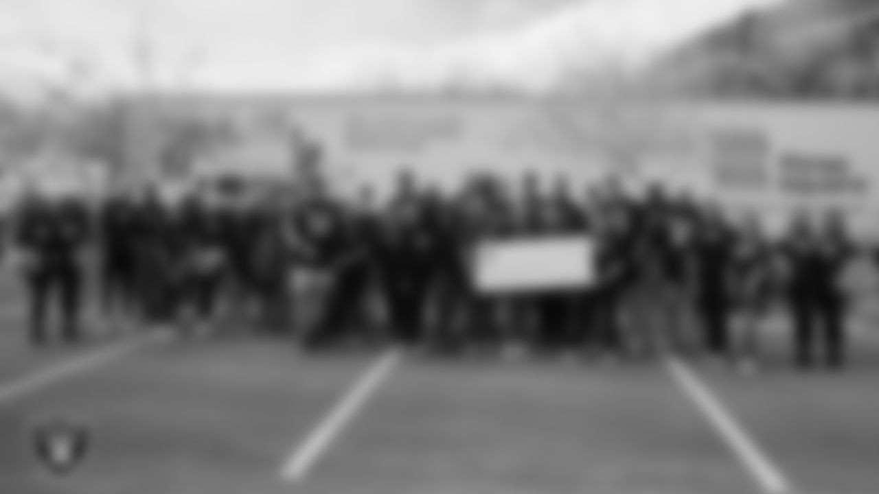 Members of the Las Vegas Raiders and Three Square pose for a photo with a check donation from TNF for Good before they distribute Thanksgiving meals to families during Turkey Time with the O-Line at Allegiant Stadium.