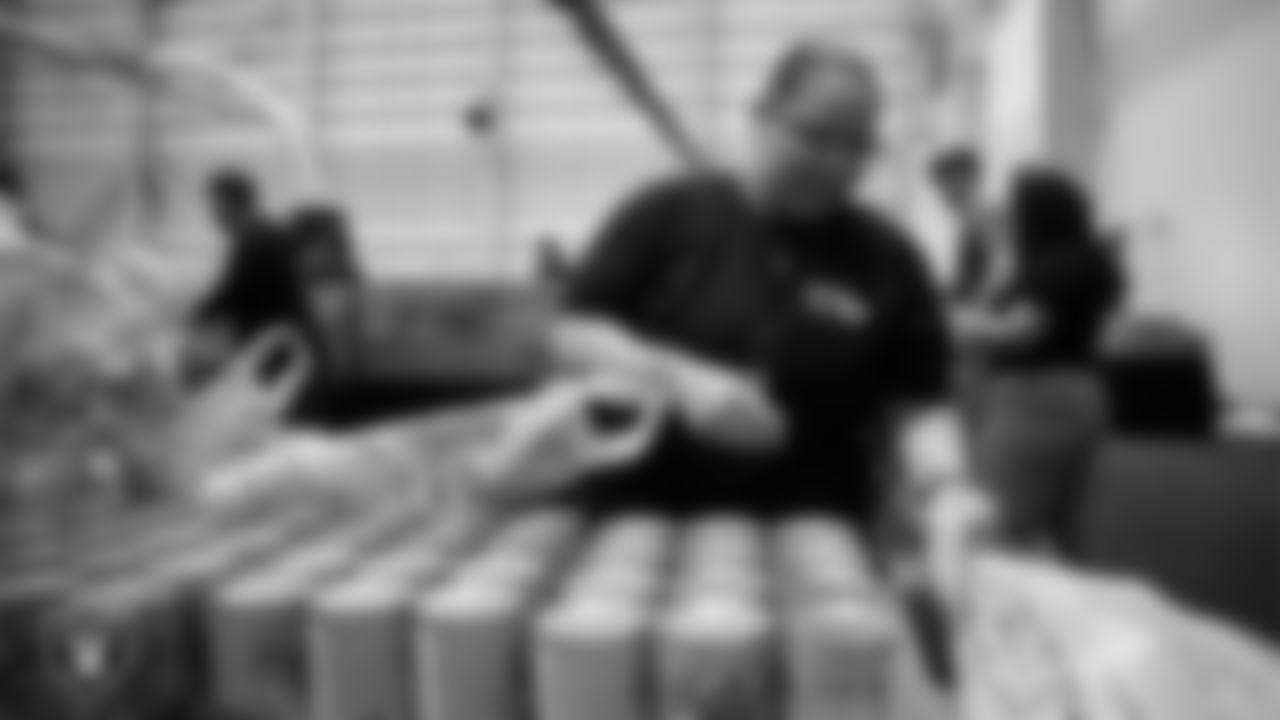 Las Vegas Raiders staff members help pack meals during the Raiders Holiday Meal Packing Party at Intermountain Health Performance Center.